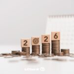 Moedas com blocos "2026" e calendário ao fundo. Decisão de venda.