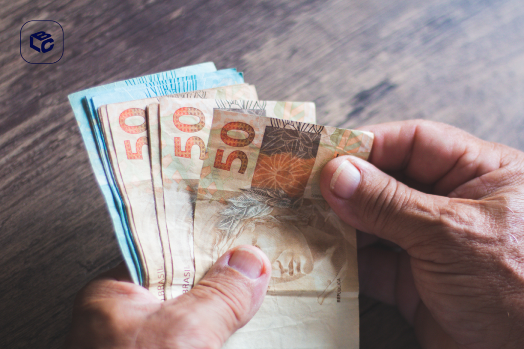 Mãos segurando notas de 50 reais, ilustrando precatório em divórcio.
