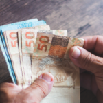 Mãos segurando notas de 50 reais, ilustrando precatório em divórcio.