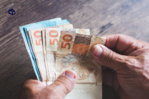 Mãos segurando notas de 50 reais, ilustrando precatório em divórcio.
